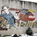 Woody Guthrie - Guthrie zůstal populární desetiletí po jeho smrti; tato nástěnná malba byla malovaná v jeho rodném městě Okemah v roce 1994 -wikipedia