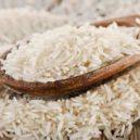 Malý domácí lexikon 7 - Uncooked rice in a wooden spoon . Selective focus