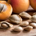 Retro rady hospodyňkám_9 - Apricot kernels and ripe apricots on a wooden background
