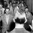 Elvis Presley - Photo of Elvis Presley and a roomful of other young men being sworn into the US Army as part of their induction at Fort Chaffee, Arkansas -wikimedia.commons –